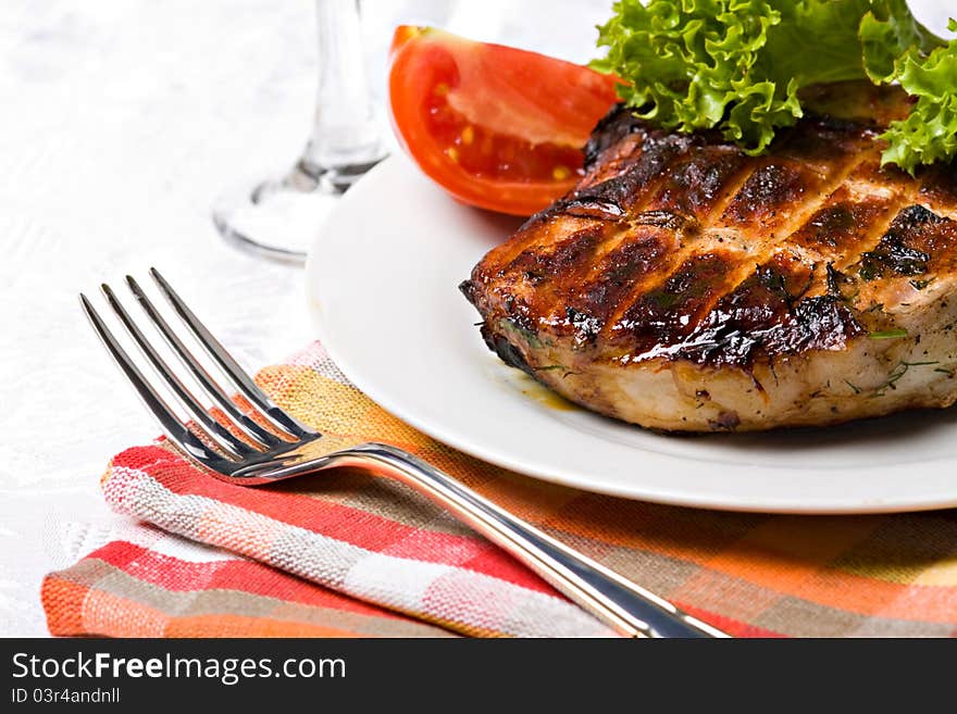 Grilled pork meat on plate with green salad