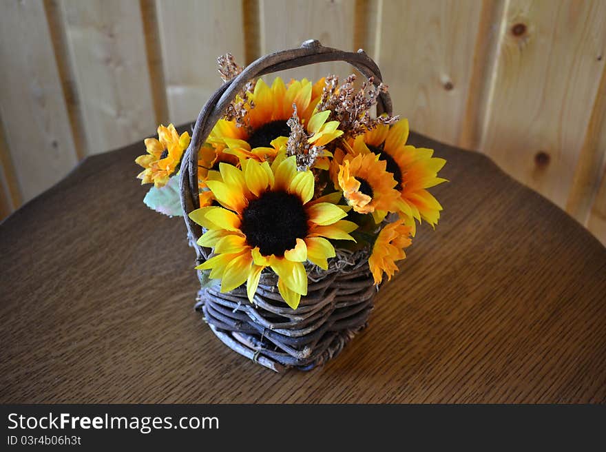 Man-made bouquet of sunflowers in a basket on a table