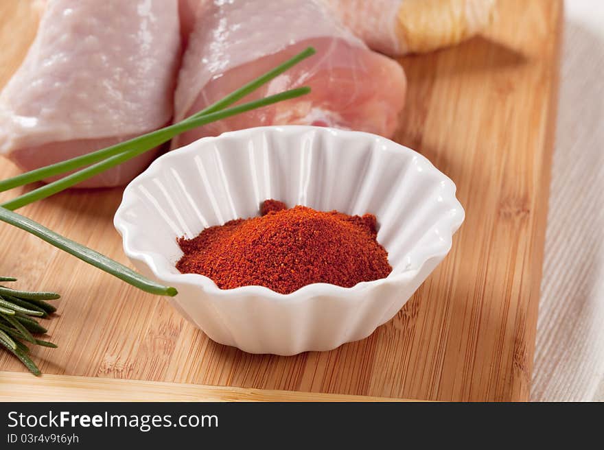 Bowl of ground paprika and raw chicken drumsticks