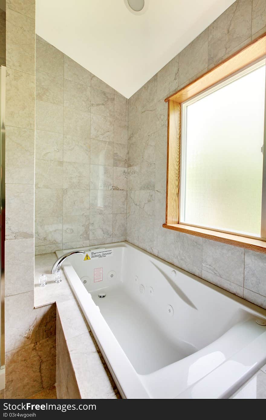 White Tub With Large Window And Tiles.