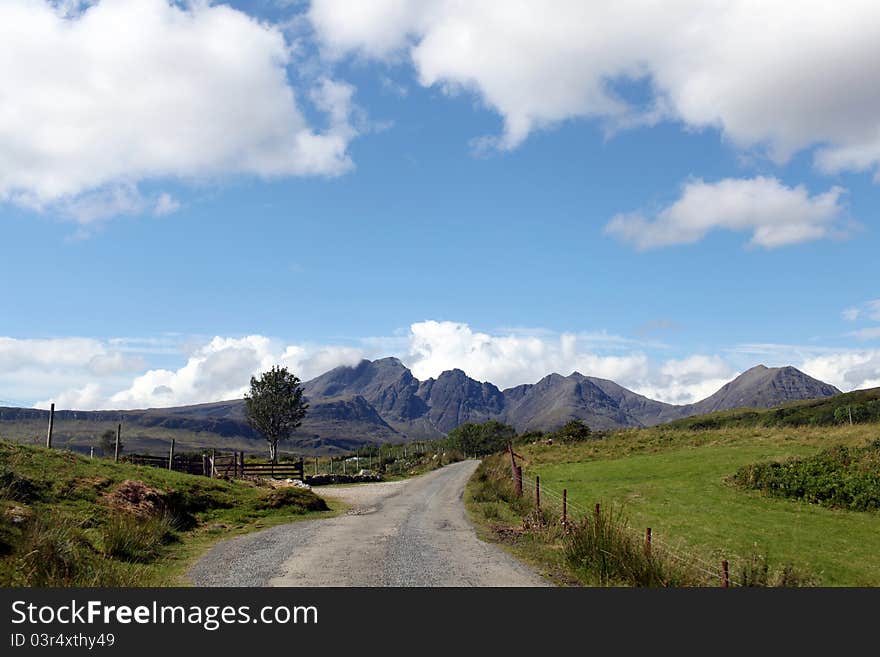 Winding road through green fields, mountains, blue sky,white clouds. Winding road through green fields, mountains, blue sky,white clouds.