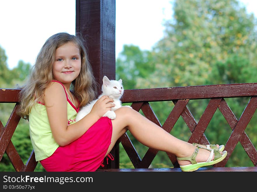 The little girl with a white kitten on a bench