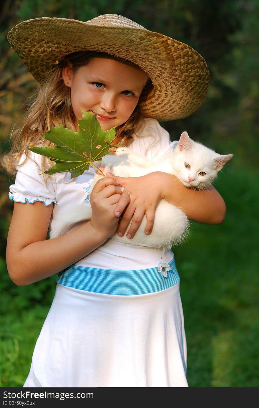 Portrait of the little girl in a hat with a kitten