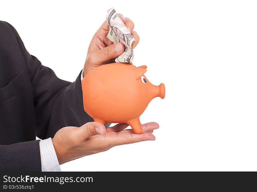 A young businessman holding a piggy bank and putting dollars inside. A young businessman holding a piggy bank and putting dollars inside