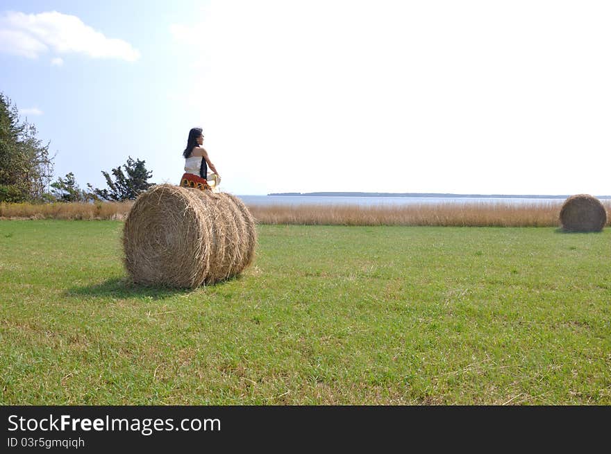 A beautiful girl is sitting on a straw roll in Prince Edward Island, Canada, watching the ocean and listening the sound, enjoying the peace and wind. A beautiful girl is sitting on a straw roll in Prince Edward Island, Canada, watching the ocean and listening the sound, enjoying the peace and wind.