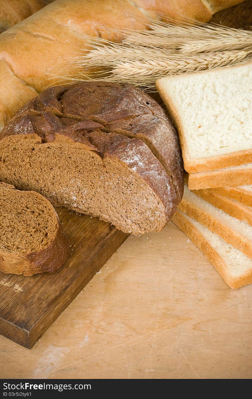 Bakery products and grain on wood background