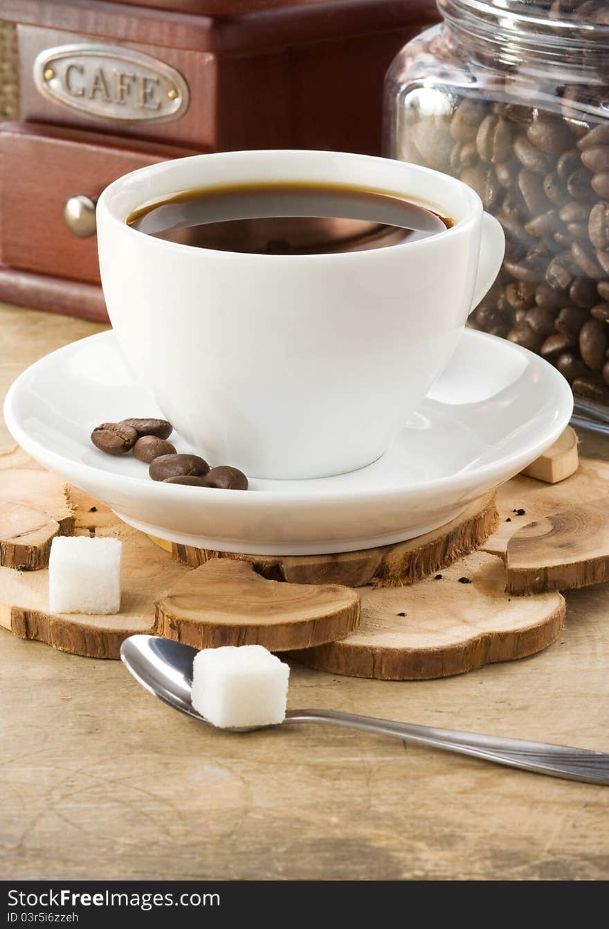 Cup of coffee and grinder with roasted beans