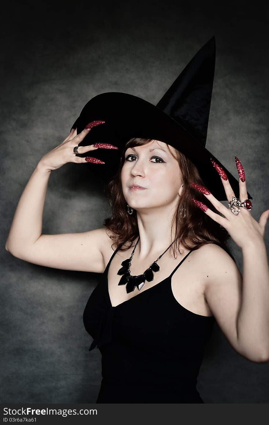 Pretty young witch with black hat and long nails. Pretty young witch with black hat and long nails