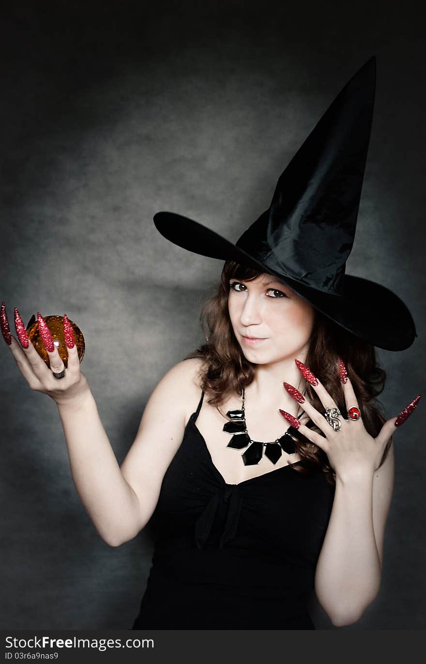 Pretty young witch with black hat, long nails and crystal ball. Pretty young witch with black hat, long nails and crystal ball