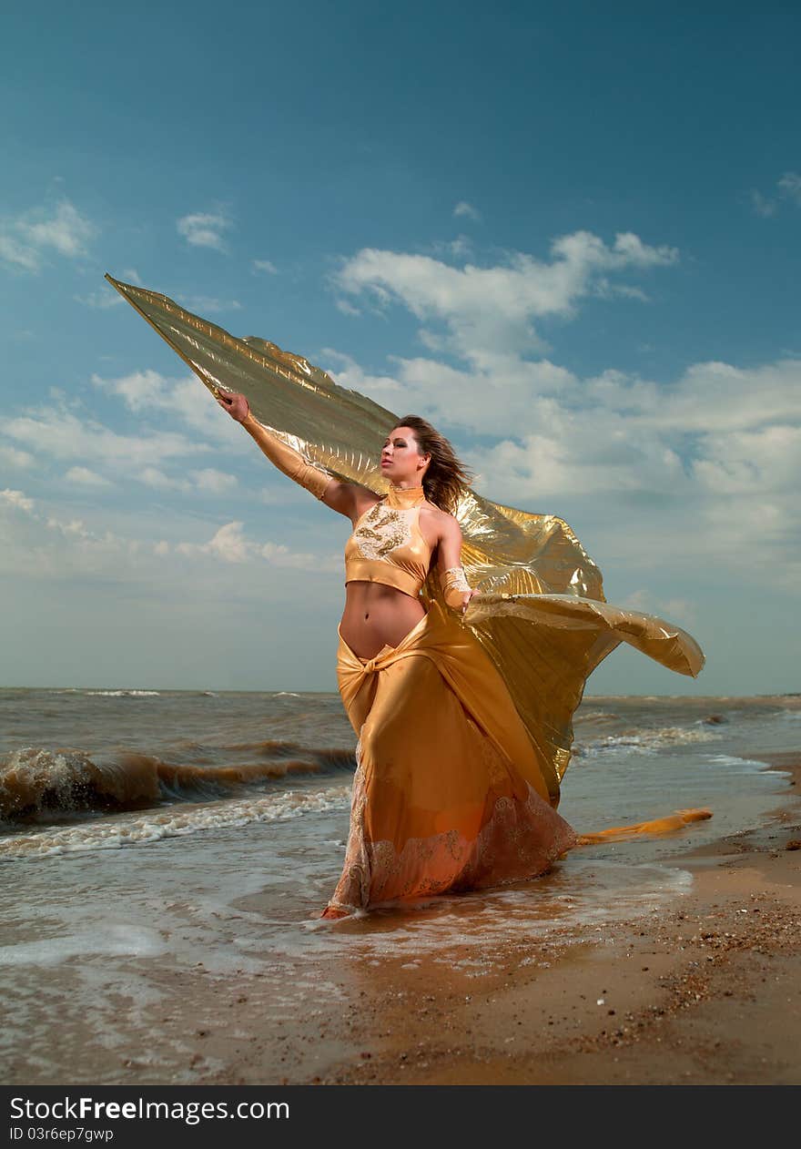 Woman in exotic dress standing on the beach