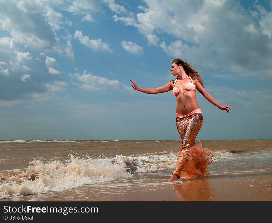 Woman in exotic dress standing on the beach