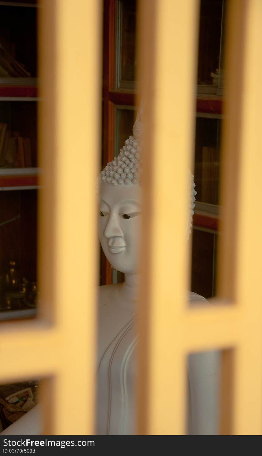 White stone buddha statue behide the metal window