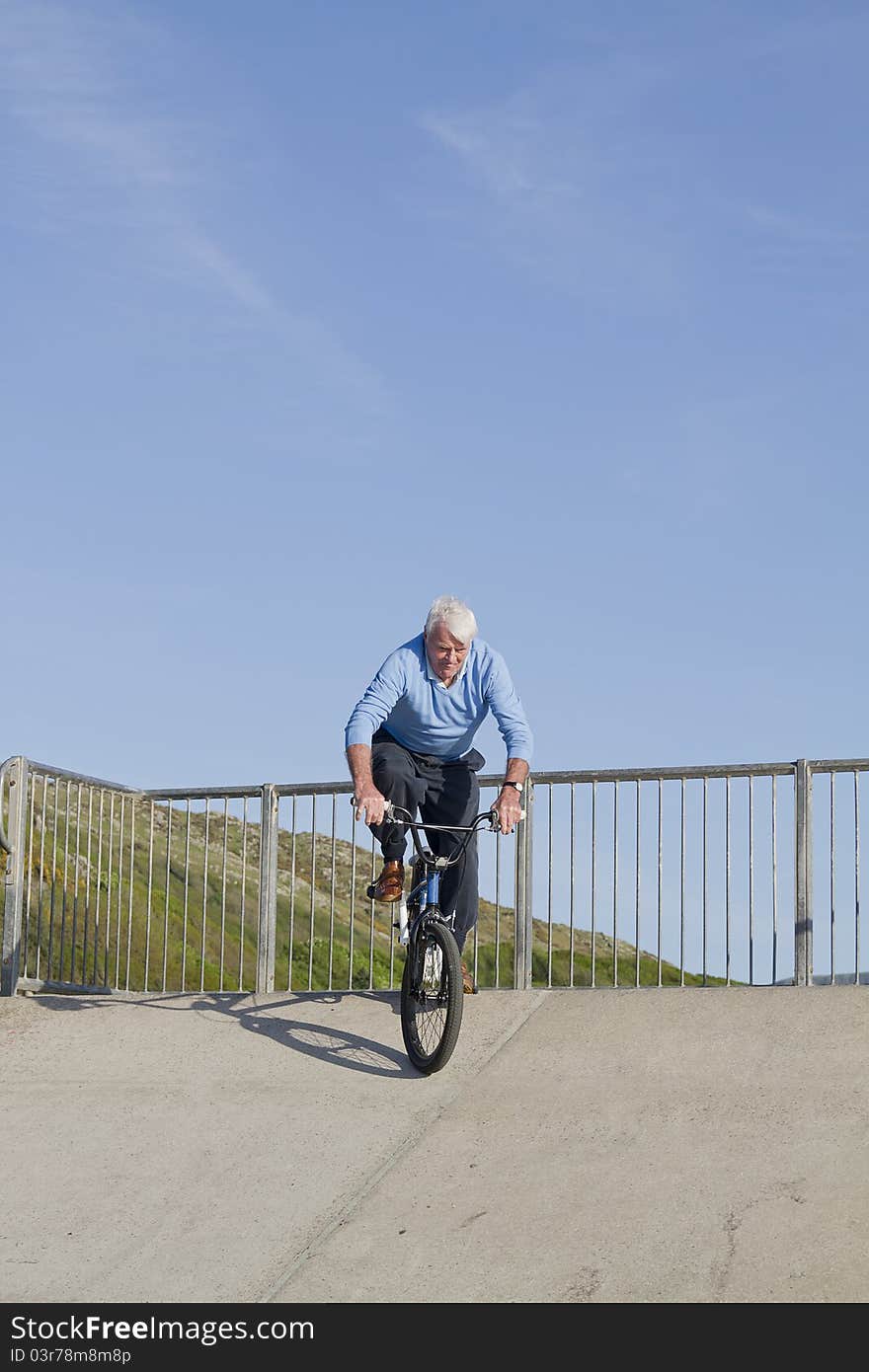 Senior man on bicycle riding down skate park. Senior man on bicycle riding down skate park