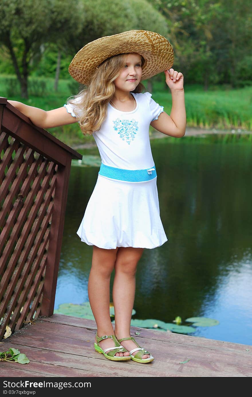 The little girl in a white dress and in a straw hat. The little girl in a white dress and in a straw hat