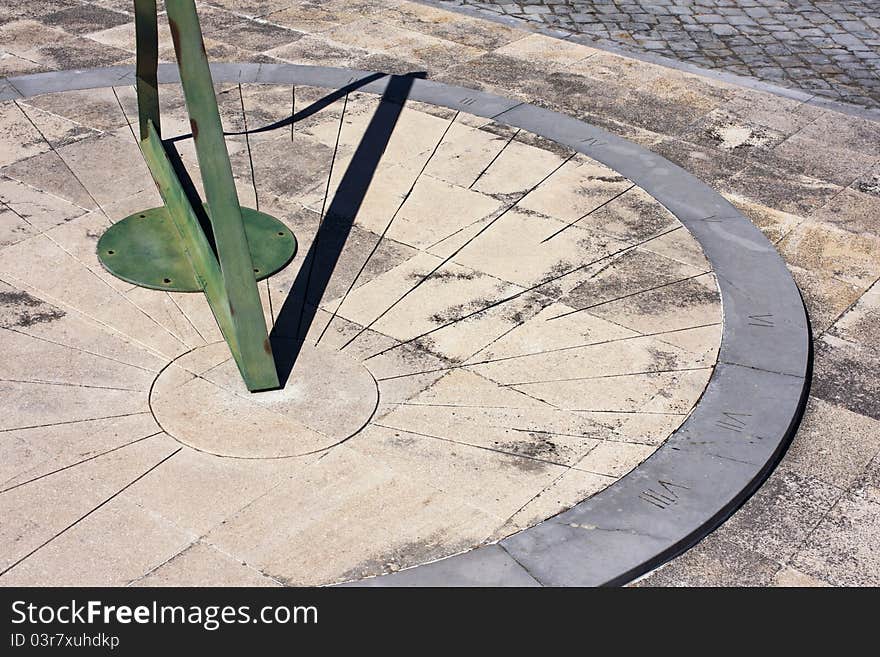 Ancient sun clock, made with stone and green iron, on the floor of a natural park