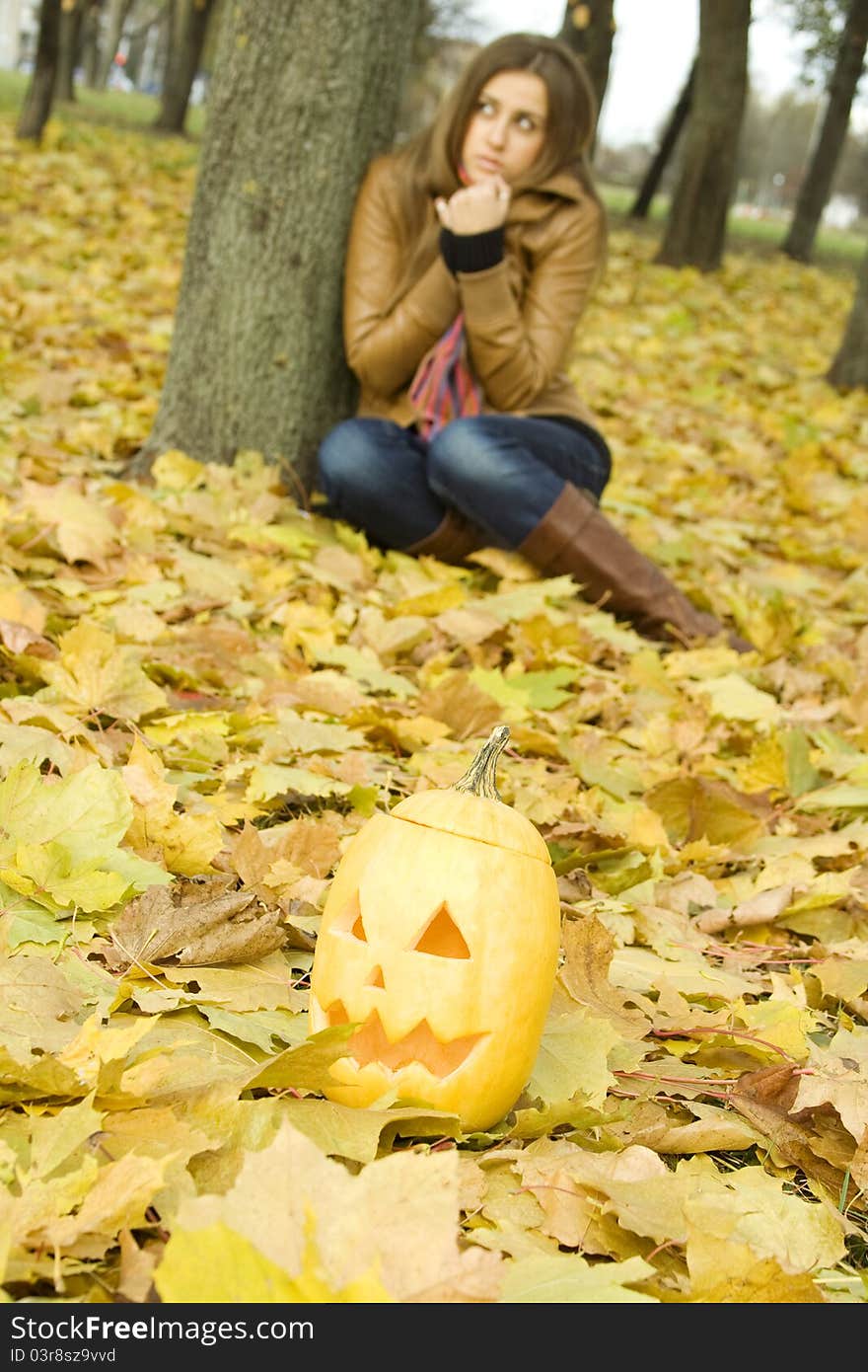 Young girl outdoors in autumn in the park with a pumpkin for Halloween