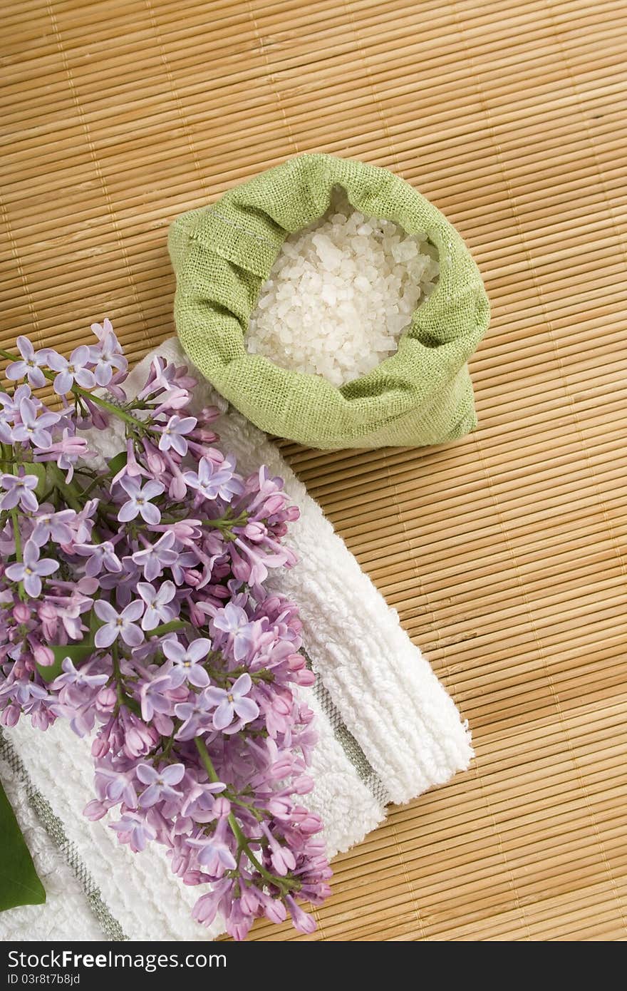 Towel, a branch of lilac and green bag with scattered sea salt. Towel, a branch of lilac and green bag with scattered sea salt