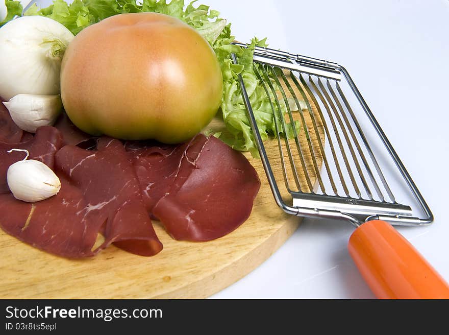 A chopping wood on white background with tomato lettuce sausage garlic onion