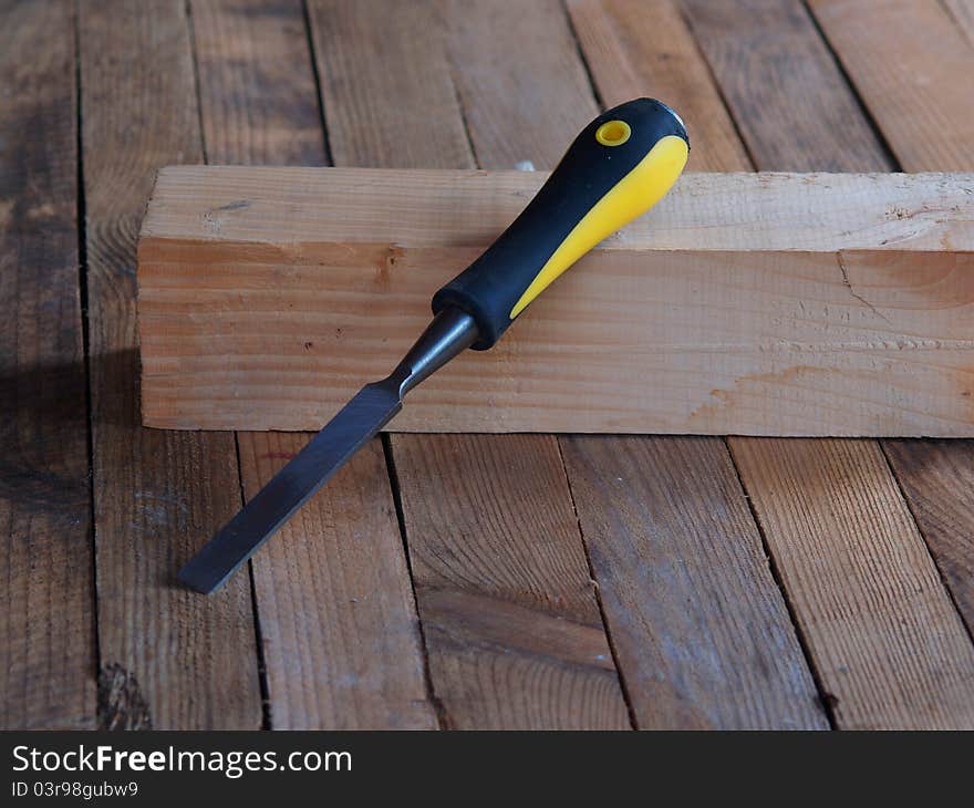 Chisel on the wood. Wooden planking background.