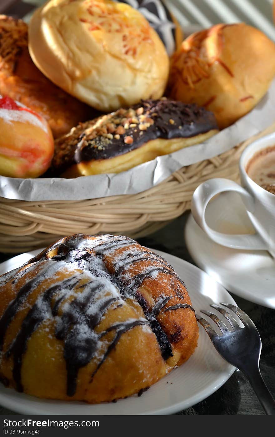 Breakfast table scene illuminated with morning light. Delicious bread sweetened with multi flavour taste served as the main menu with cappucino as the drinks. Great images for food and beverages article or any design involving food and drinks. Breakfast table scene illuminated with morning light. Delicious bread sweetened with multi flavour taste served as the main menu with cappucino as the drinks. Great images for food and beverages article or any design involving food and drinks.