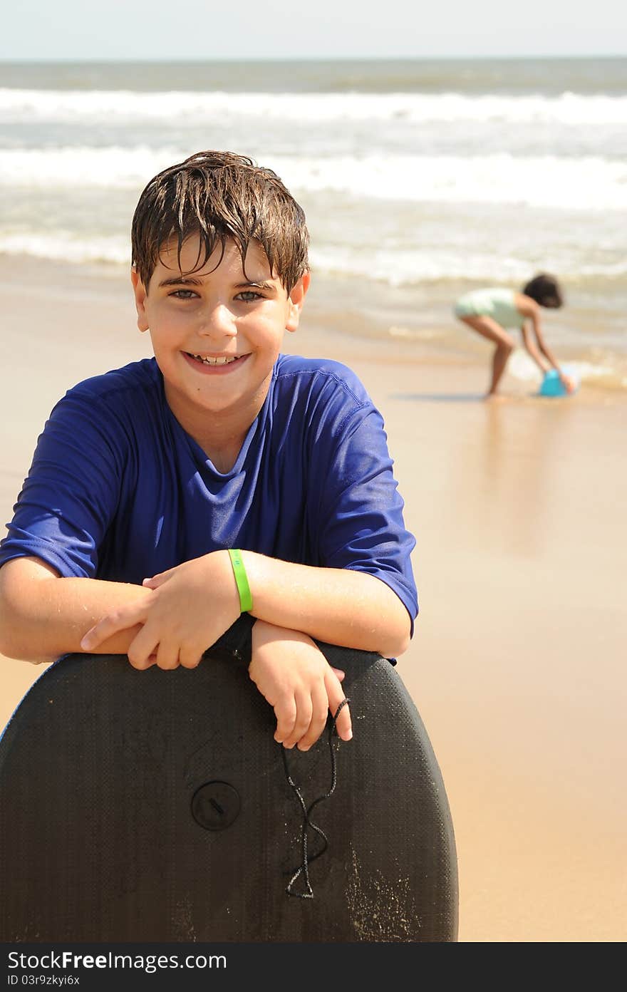 Boy with a boogie board at the ocean on the beach playing in the waves. Boy with a boogie board at the ocean on the beach playing in the waves