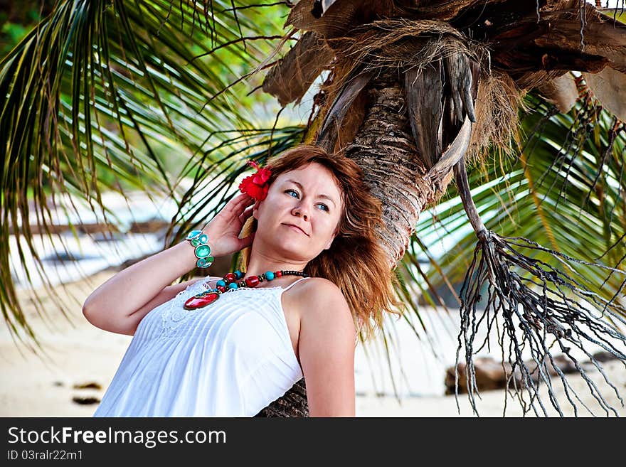 Beautiful woman with red flower in her hair resting on a palm. Beautiful woman with red flower in her hair resting on a palm