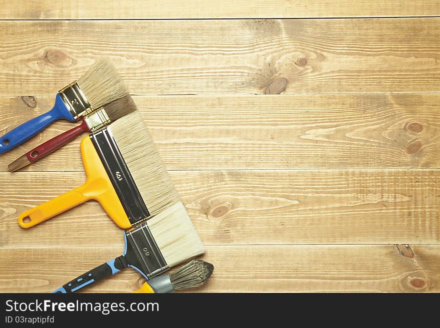 Different paintbrushes on a wooden background.