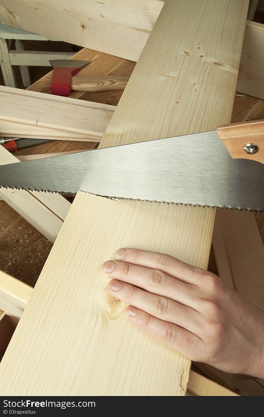 Man sawing plank on a wooden background.