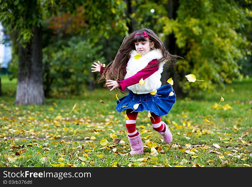 Cute little girl wearing fur coat in autumn forest