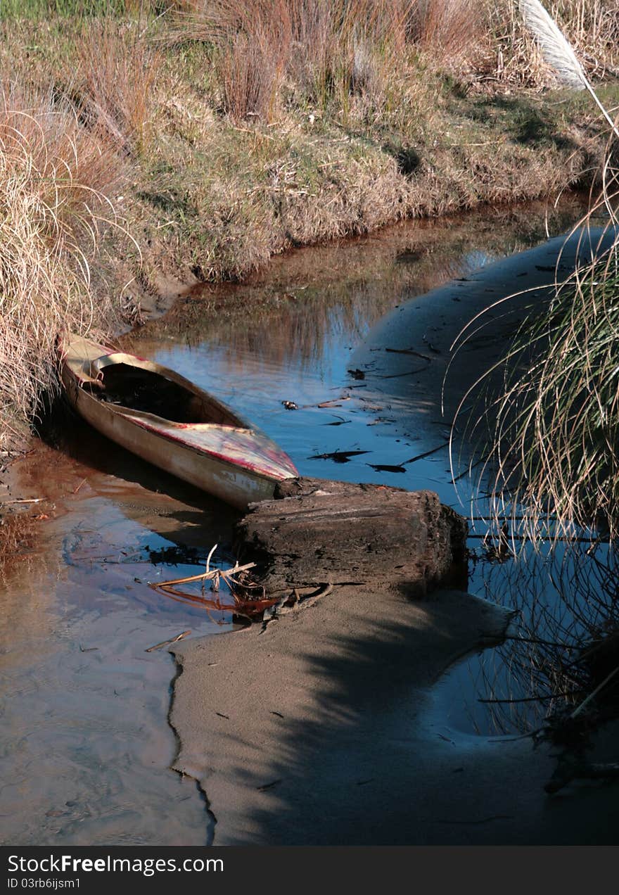 A derelict kayak sits in a tidal estuary. A derelict kayak sits in a tidal estuary