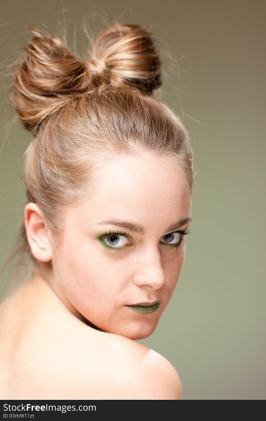 Portrait of beautiful young pretty woman with blond cockade on green background. Portrait of beautiful young pretty woman with blond cockade on green background