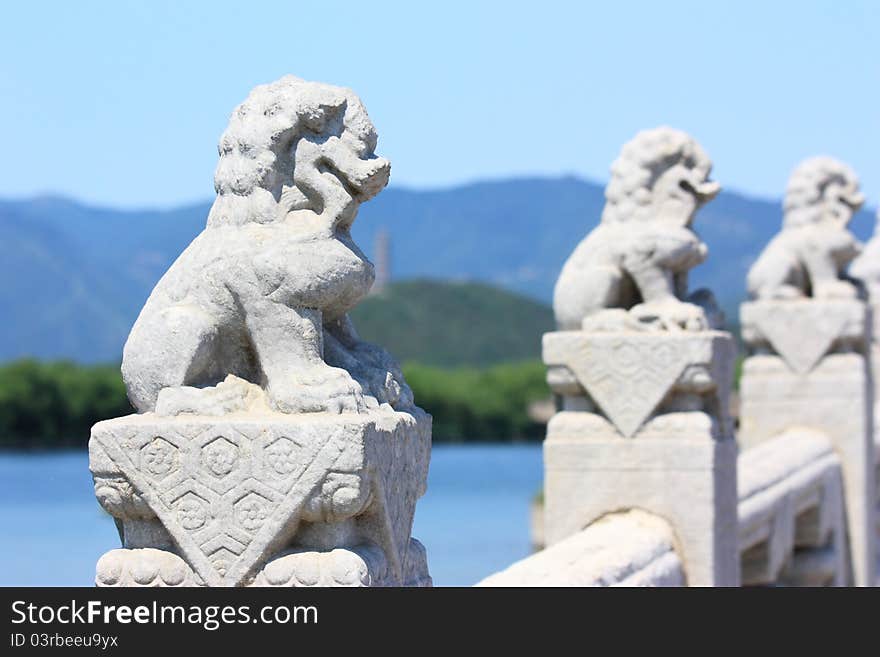 In the Summer Palace, these 544 carved white marble lions, in distinctive postures, sit at the column of the parapets on the 17-arch Bridge, which looks like a rainbow arching over the lake water.Beijing, China. In the Summer Palace, these 544 carved white marble lions, in distinctive postures, sit at the column of the parapets on the 17-arch Bridge, which looks like a rainbow arching over the lake water.Beijing, China