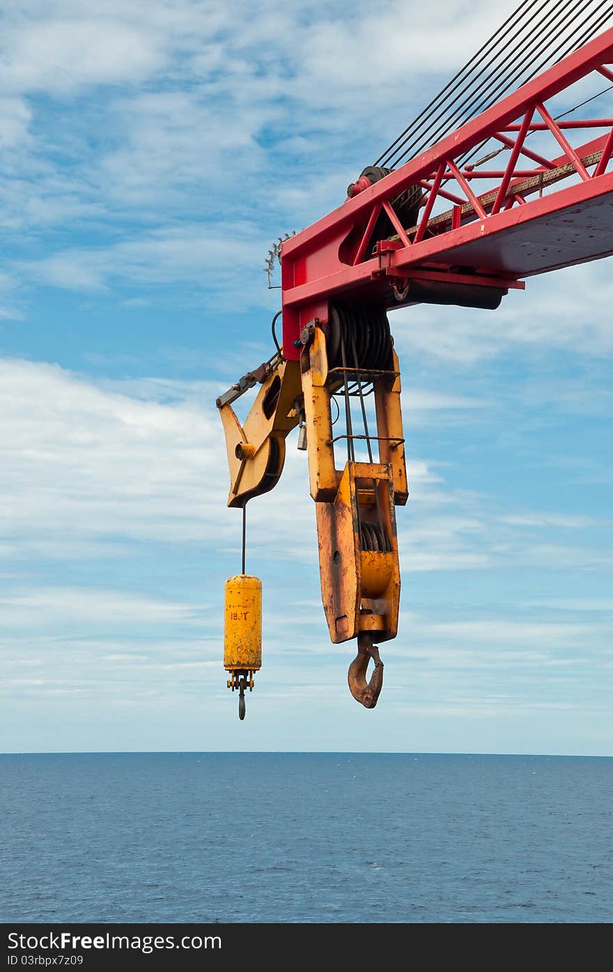 A boom of a crane on a semi-submersible drilling unit with a hook hovering over the horizon line. A boom of a crane on a semi-submersible drilling unit with a hook hovering over the horizon line.