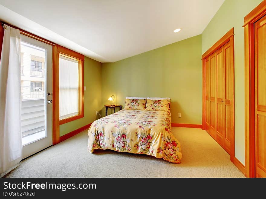 Large bright green bedroom with floral bedding and white curtains. Large bright green bedroom with floral bedding and white curtains.