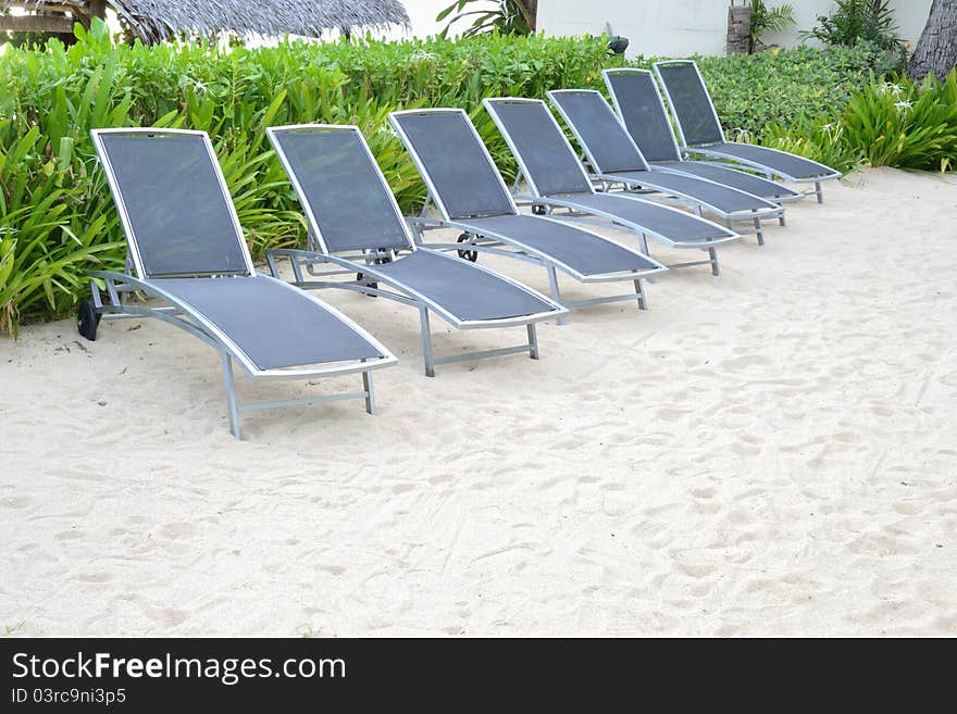 Row of blue beach chair on clear sand beach.