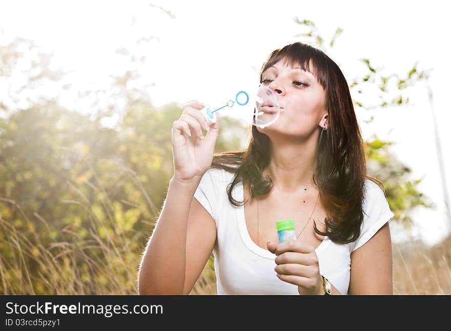 Young beautiful girl blowing bubbles outdoors