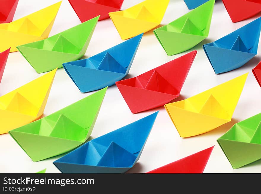 Several colored paper boats on white background