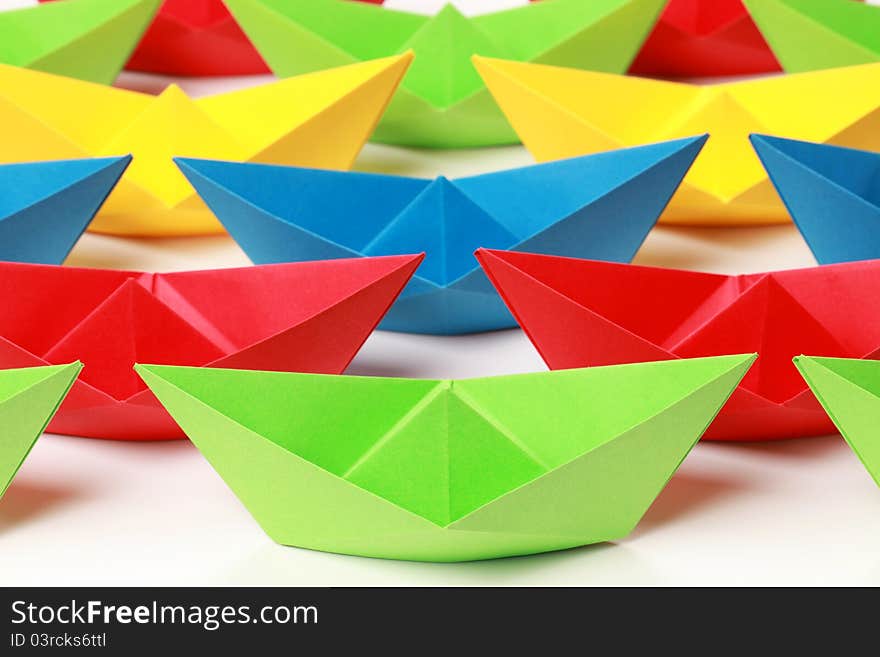 Several colored paper boats on white background