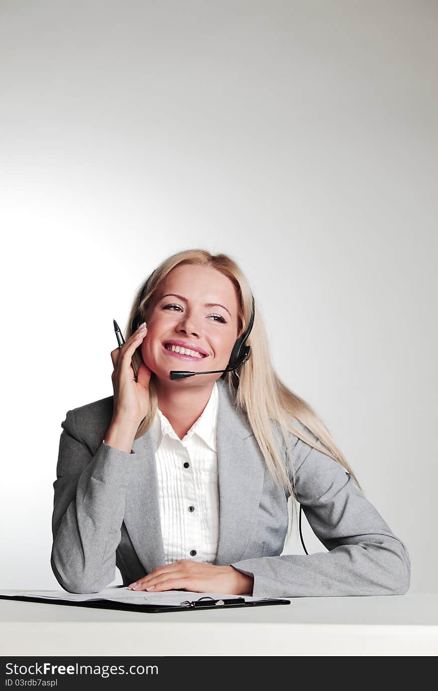 Business woman in a headset writing in notebook. Business woman in a headset writing in notebook