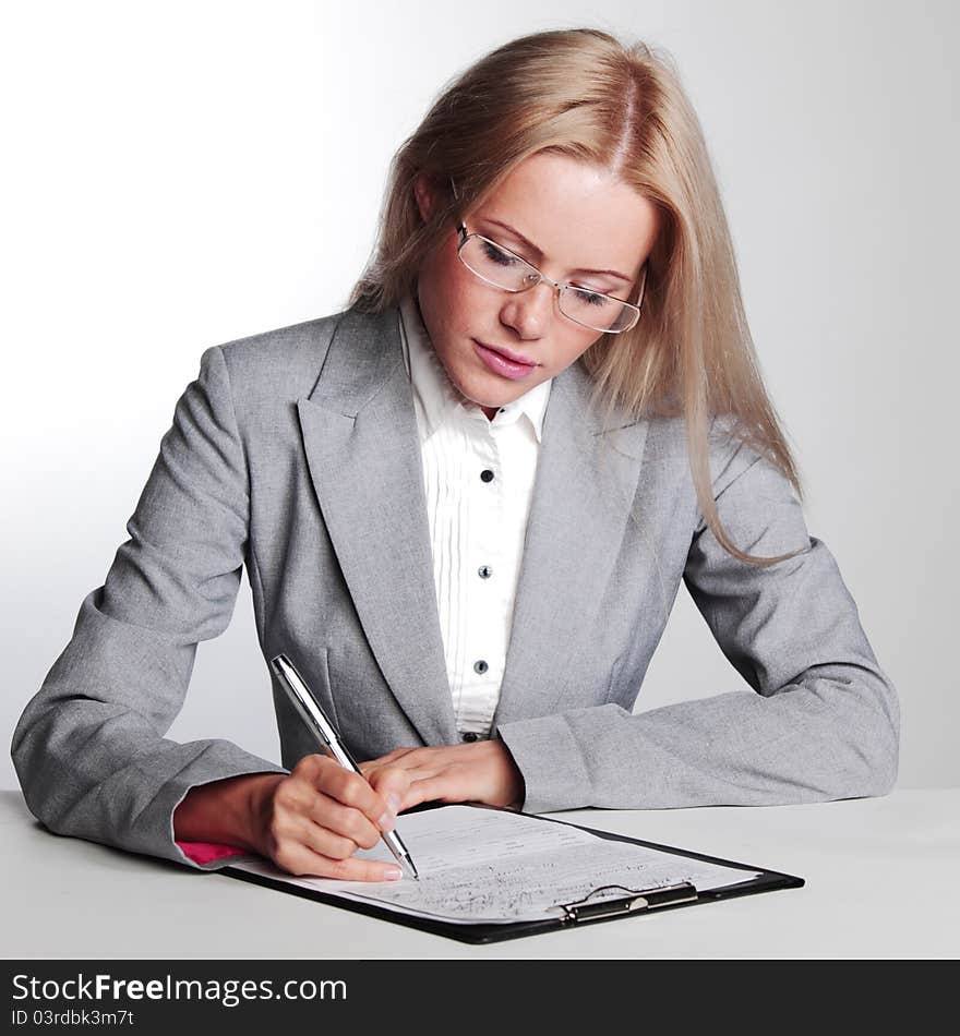 Business woman writing in notebook on a gray background