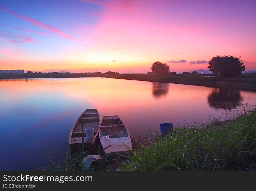 Sunset along the pond with isolated boats