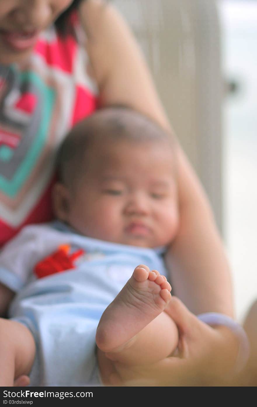 A baby lying in mother's arm with his foot close-up. A baby lying in mother's arm with his foot close-up