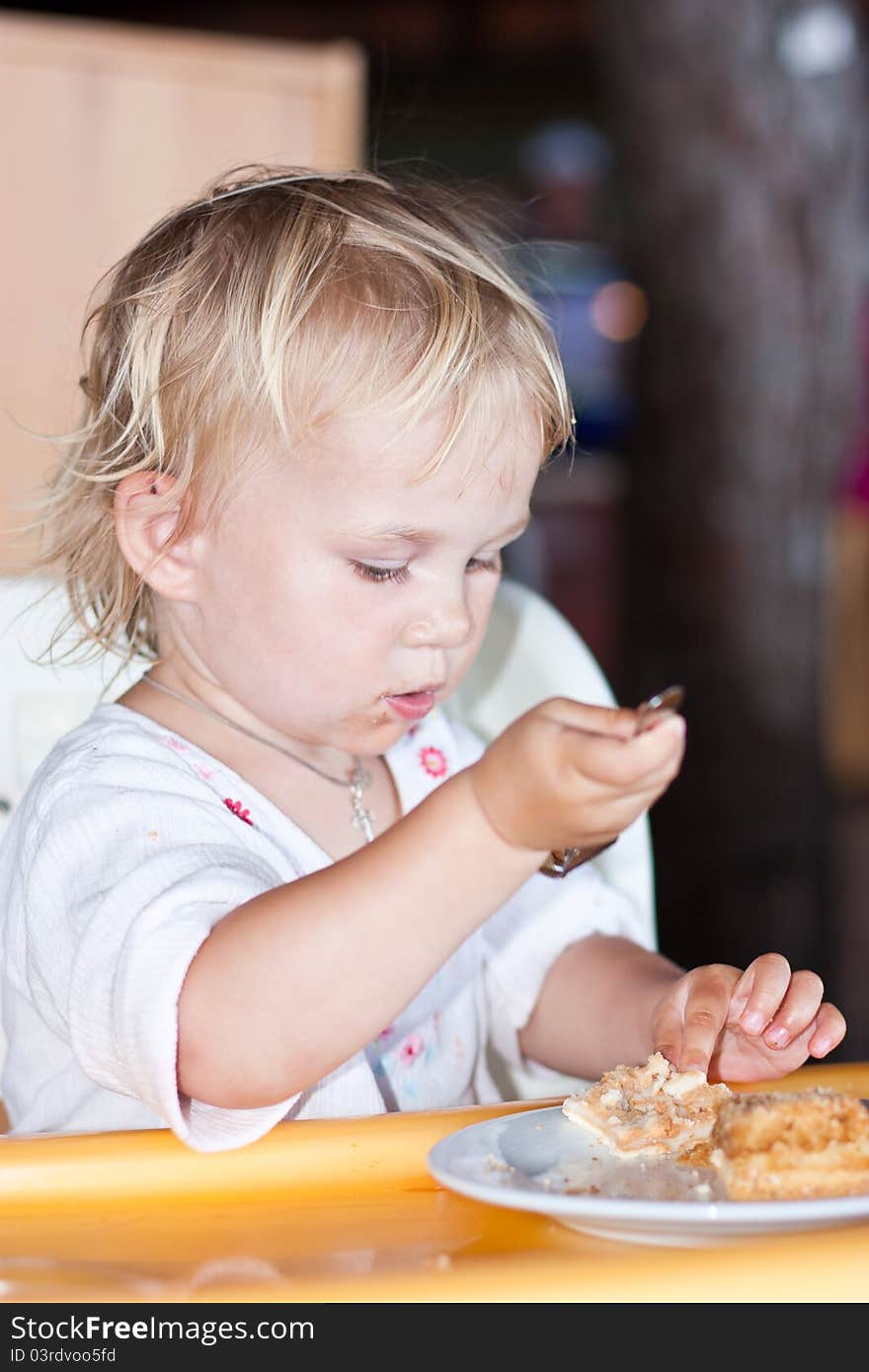 Adorable Baby Eating Cake In A Chair