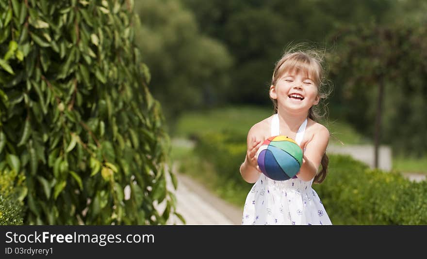 Little girl playing ball in the park on summer