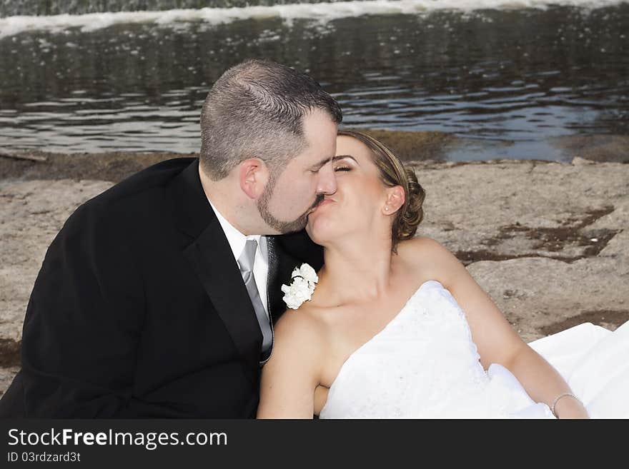 Wedding couple kissing by the waterfall. Wedding couple kissing by the waterfall