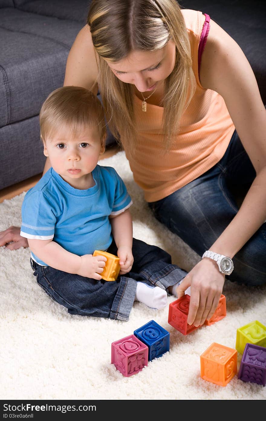 Young mother playing with baby boy ( 1 year old ) at home.