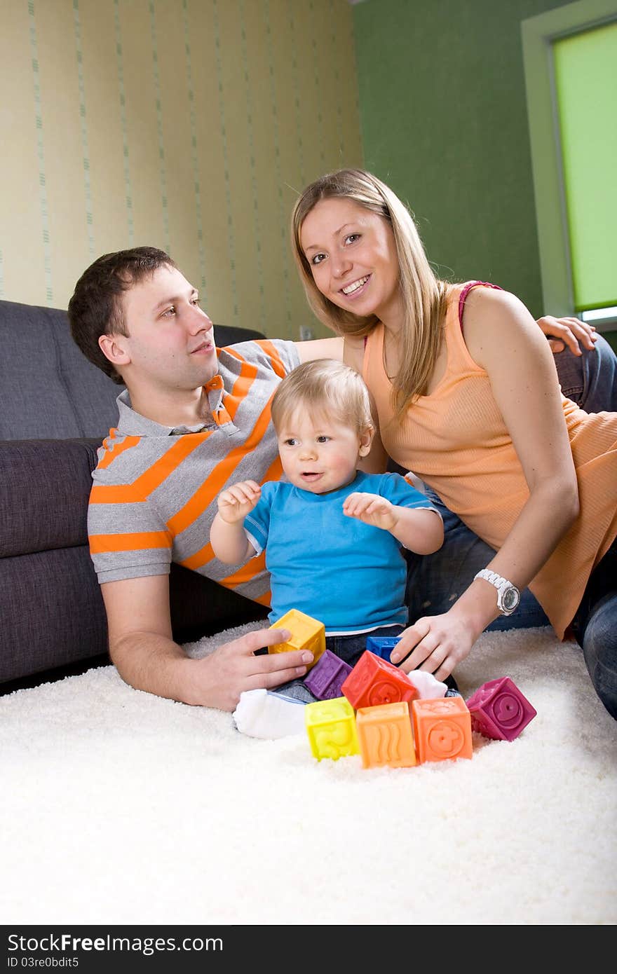 Family with baby boy sitting on floor at home and playing together. Family with baby boy sitting on floor at home and playing together.