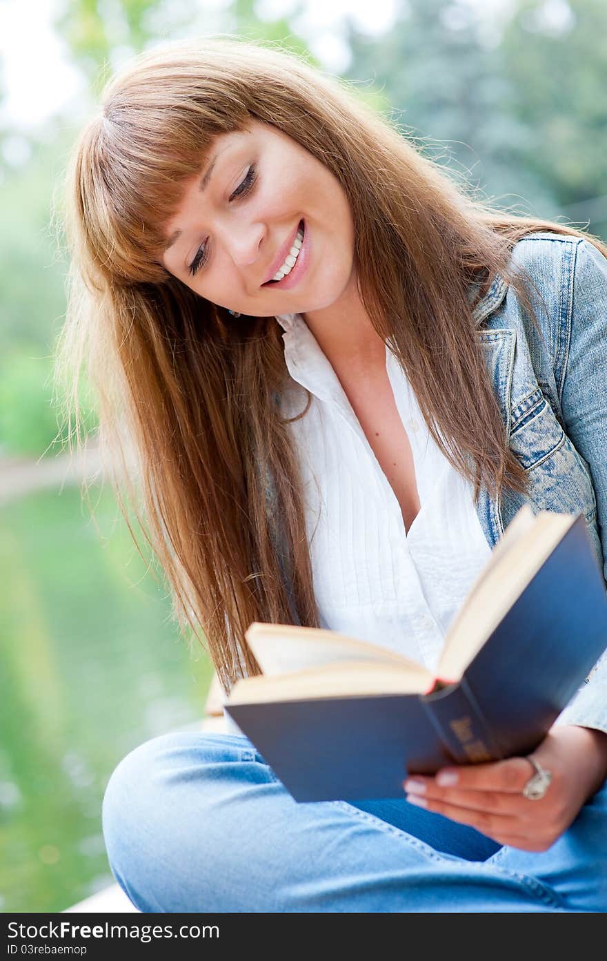 Young woman reading a book sitting on the bench