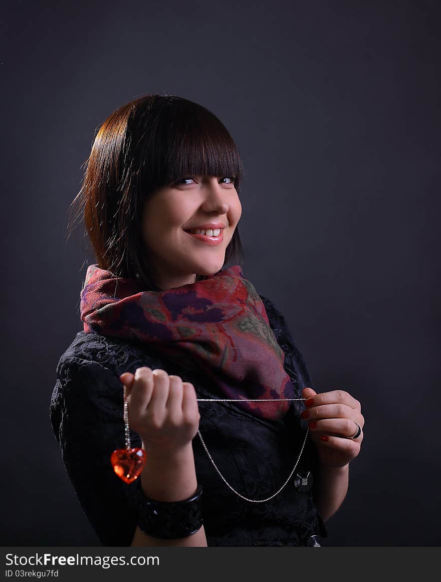 Young beautiful woman holding heart, on dark background