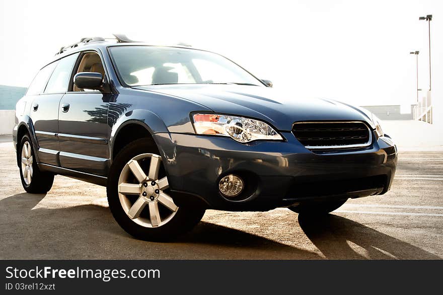 Front and side view of blue wagon on parking lot, backlit. Front and side view of blue wagon on parking lot, backlit